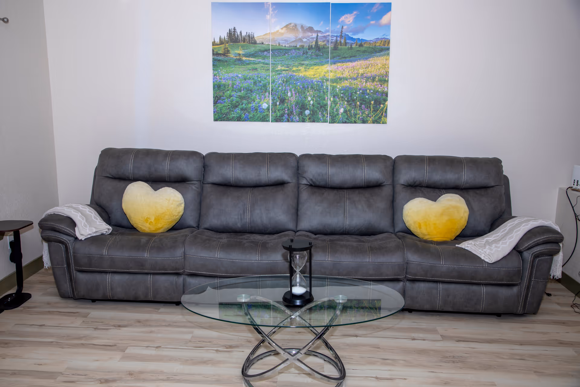 Grey sofa with yellow heart cushions in a living room with a glass coffee table.