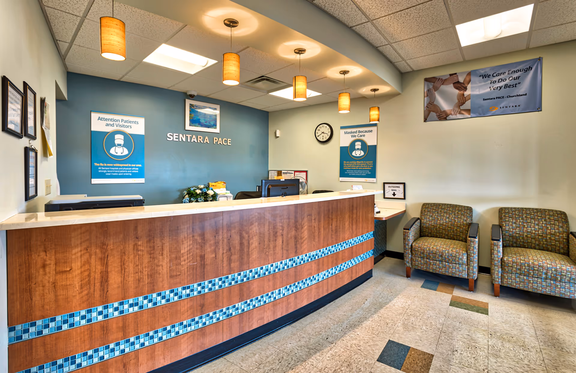 Reception desk in a Sentara PACE facility lobby with seating and posters.