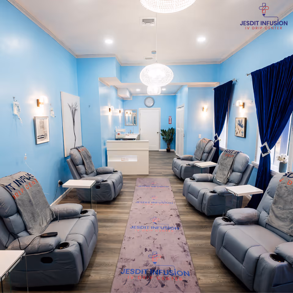 Bright blue infusion lounge with reclining chairs, curtains, and a reception desk at the far end.