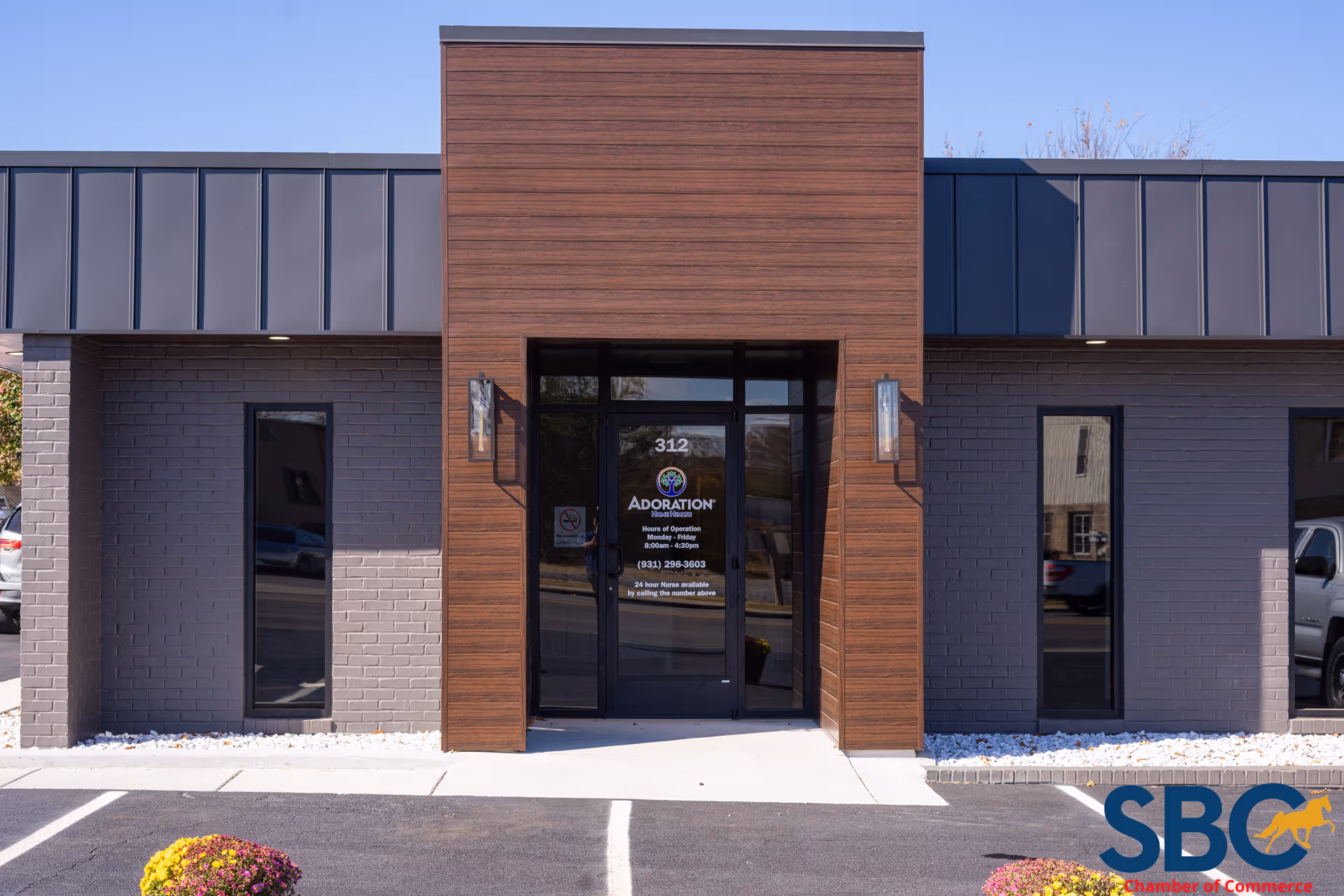 Modern facility entrance with wooden panel facade, glass doors, and gray brick exterior.