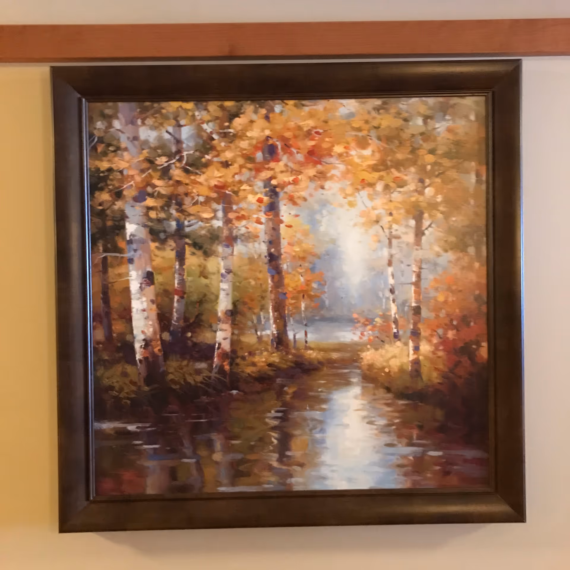 Framed autumn forest painting with birch trees and reflective water hangs on a wall.
