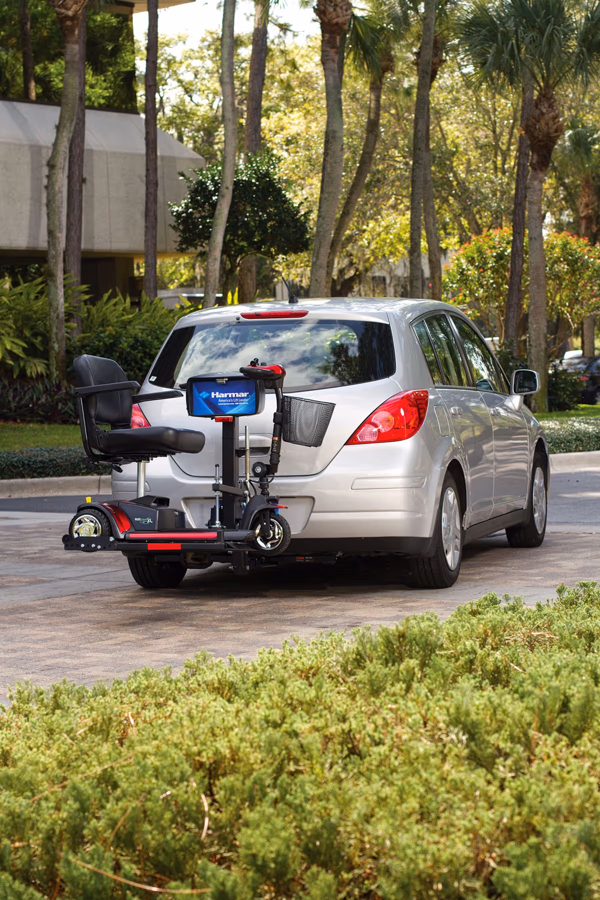 Silver car parked outdoors with a rear hitch-mounted mobility scooter carrier.