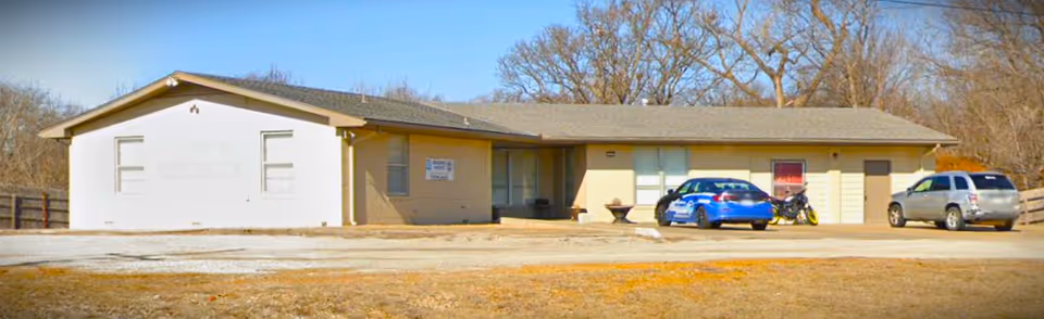 Exterior view of a single-story facility with parked cars in front.
