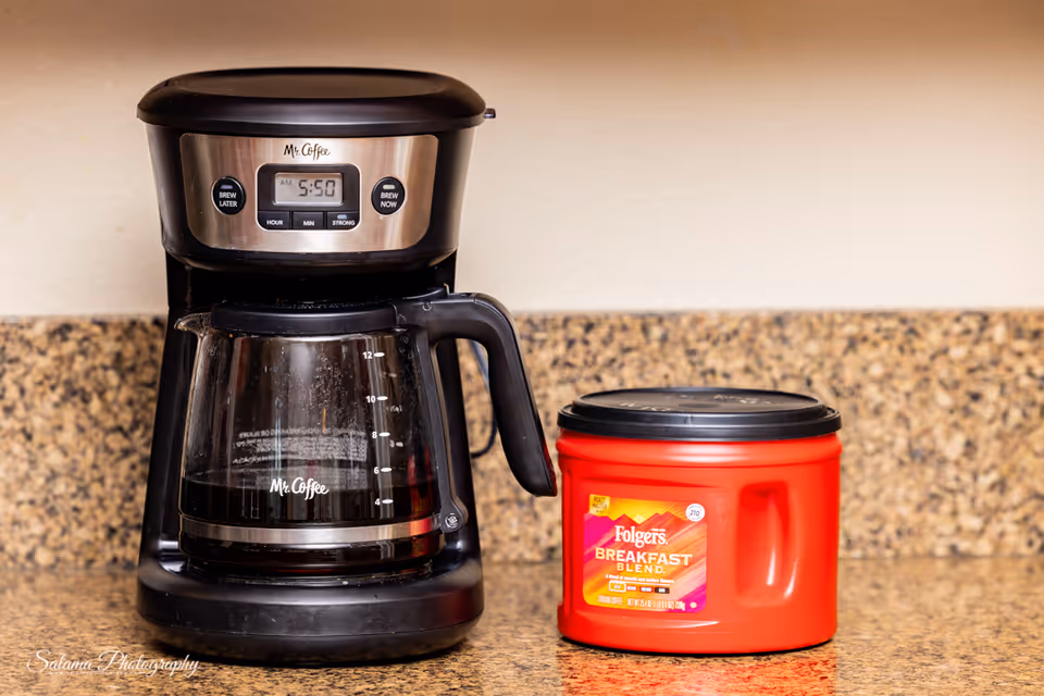 Coffee maker and red canister sit on a granite kitchen counter in a care facility.