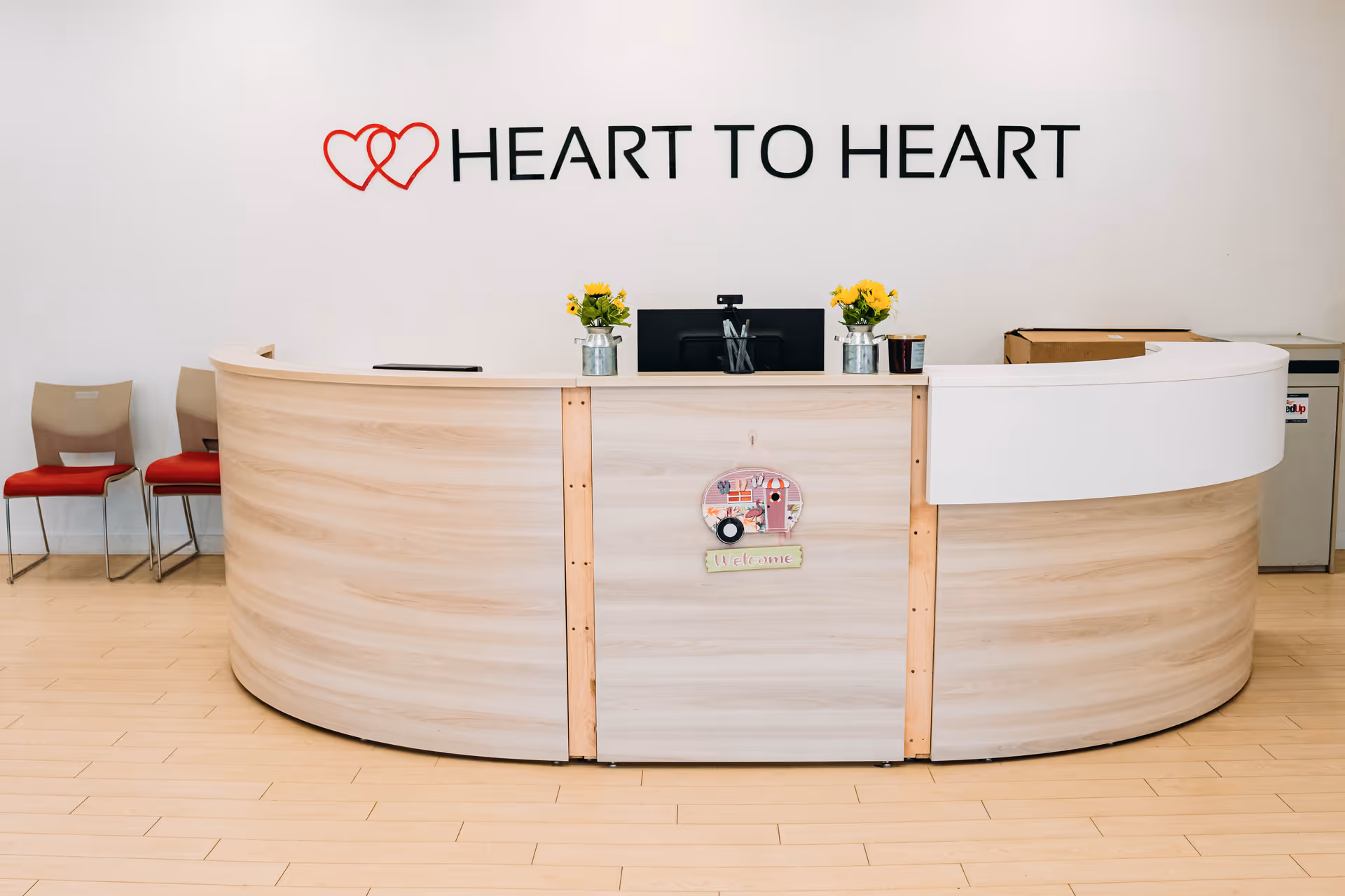 Curved wooden reception desk in a bright interior with Heart to Heart signage.