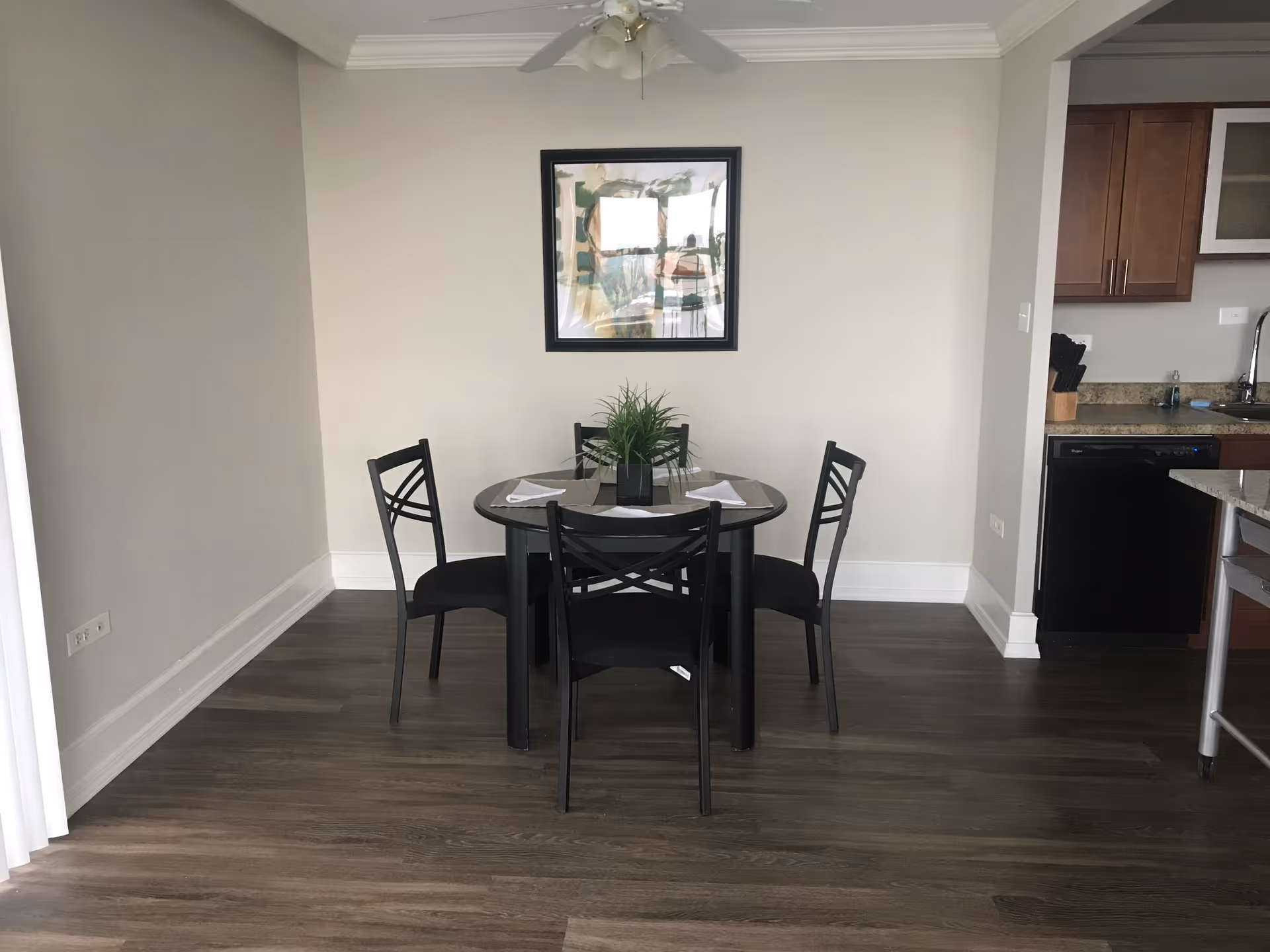 Round dining table with four chairs in a neutral dining area beside the kitchen.