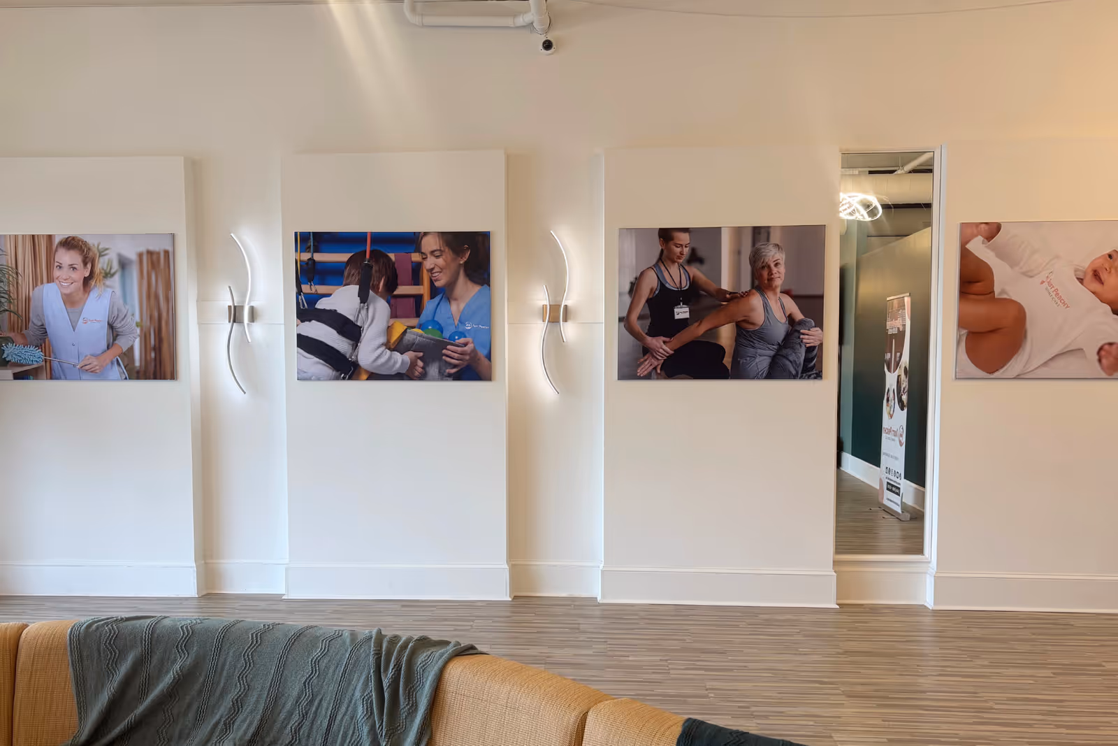 Modern interior lounge with wall-mounted photo panels and a beige sectional sofa.