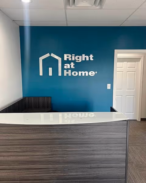 Reception desk against teal wall with Right at Home logo, doorway on the right