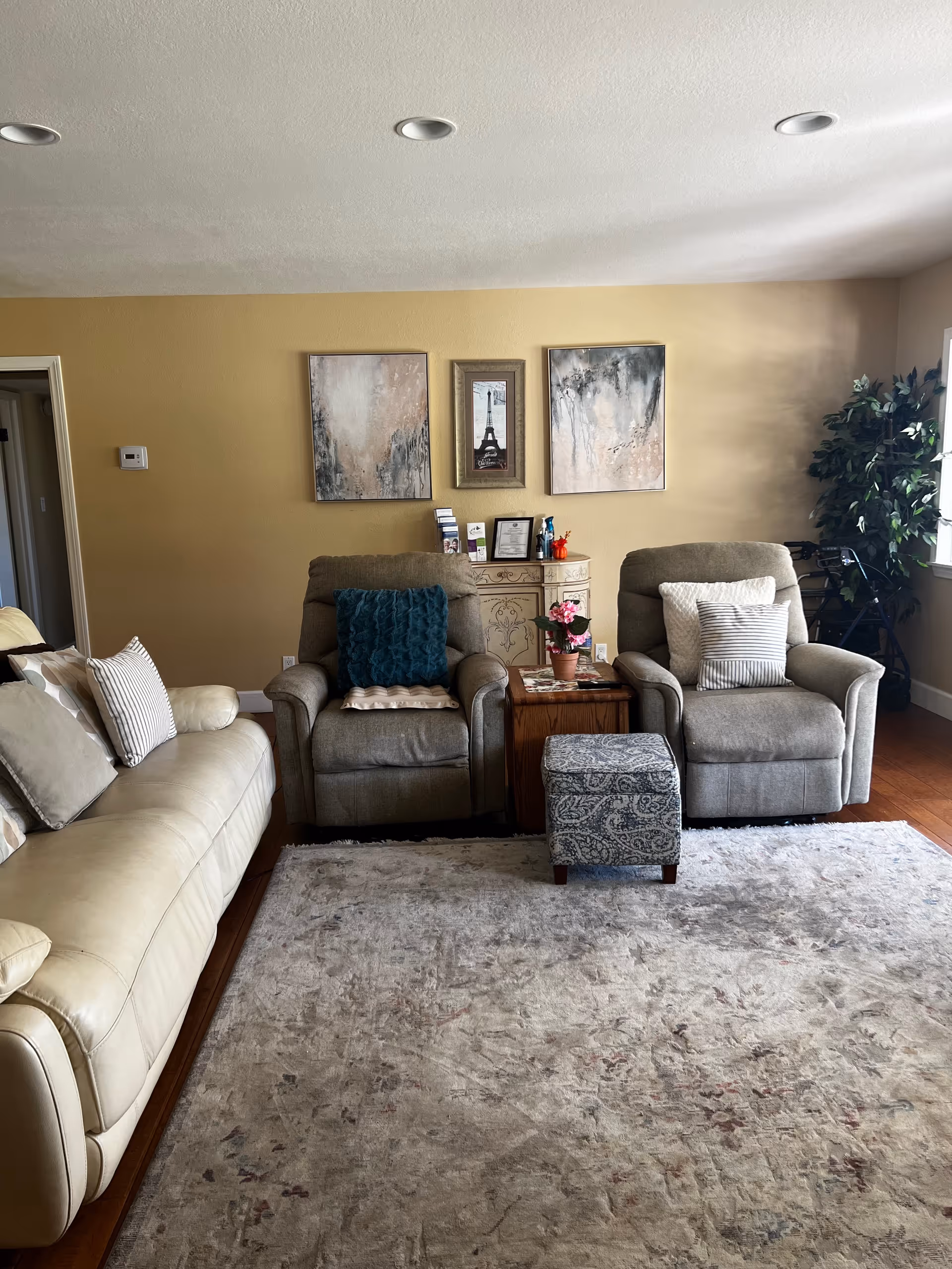 Interior living room of Conejo Valley Home Care with beige couches, chairs, rug, and wall art.