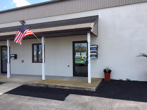 Front exterior of Visiting Angels Senior Home Care building with entrance, awning, and flag.