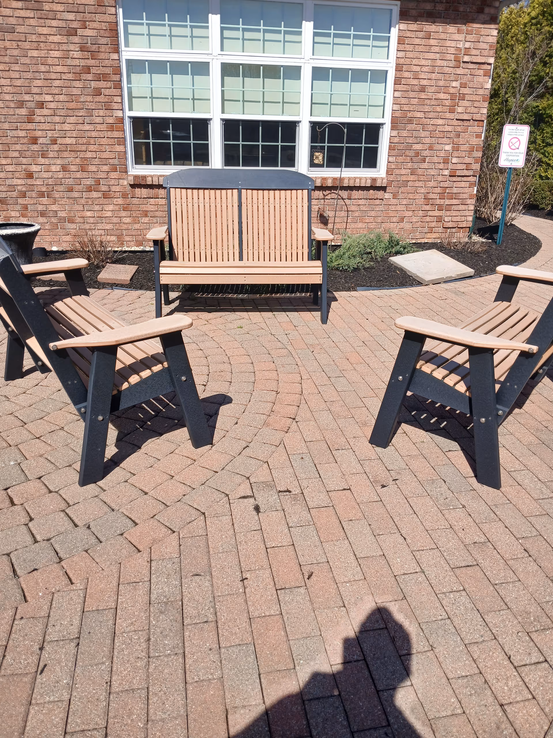 Outdoor brick-paved patio with wooden chairs arranged in a circular seating area.