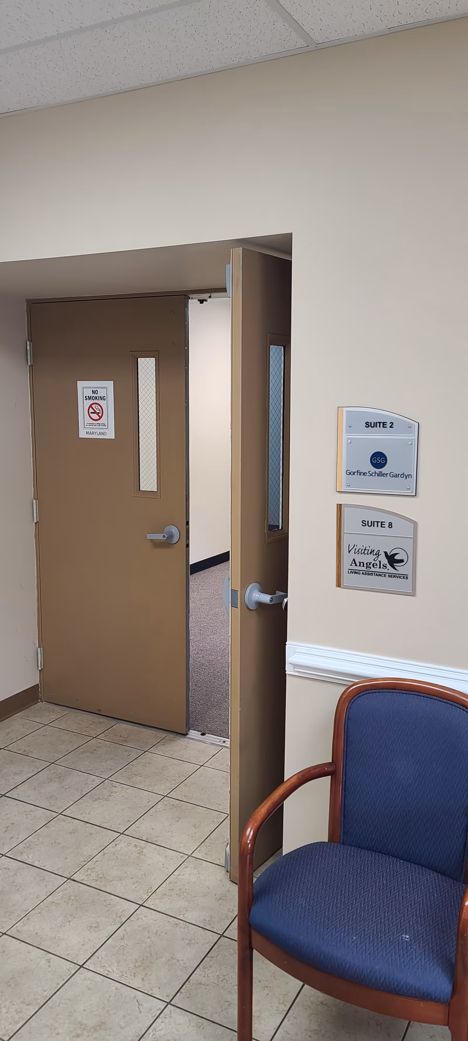 Interior hallway in a senior home with suite signs and a blue chair.