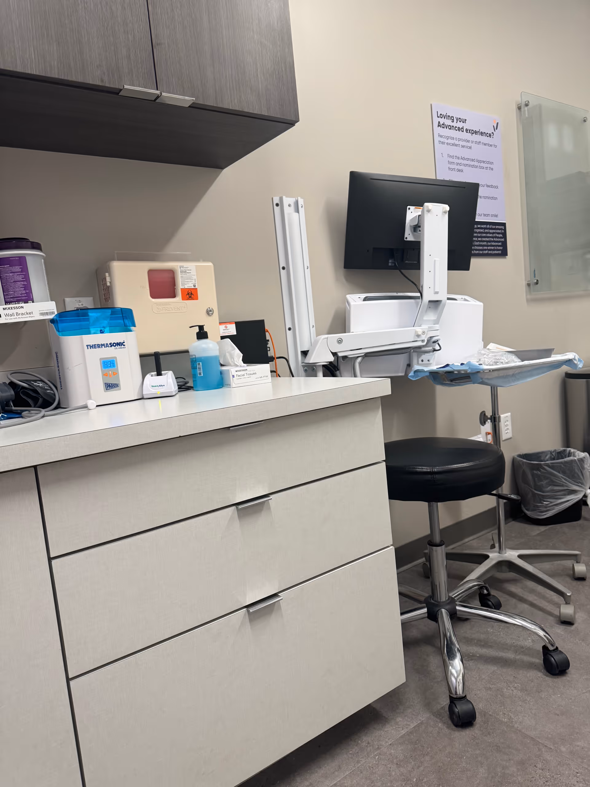 Clinical examination room with a counter, computer, and medical supplies.