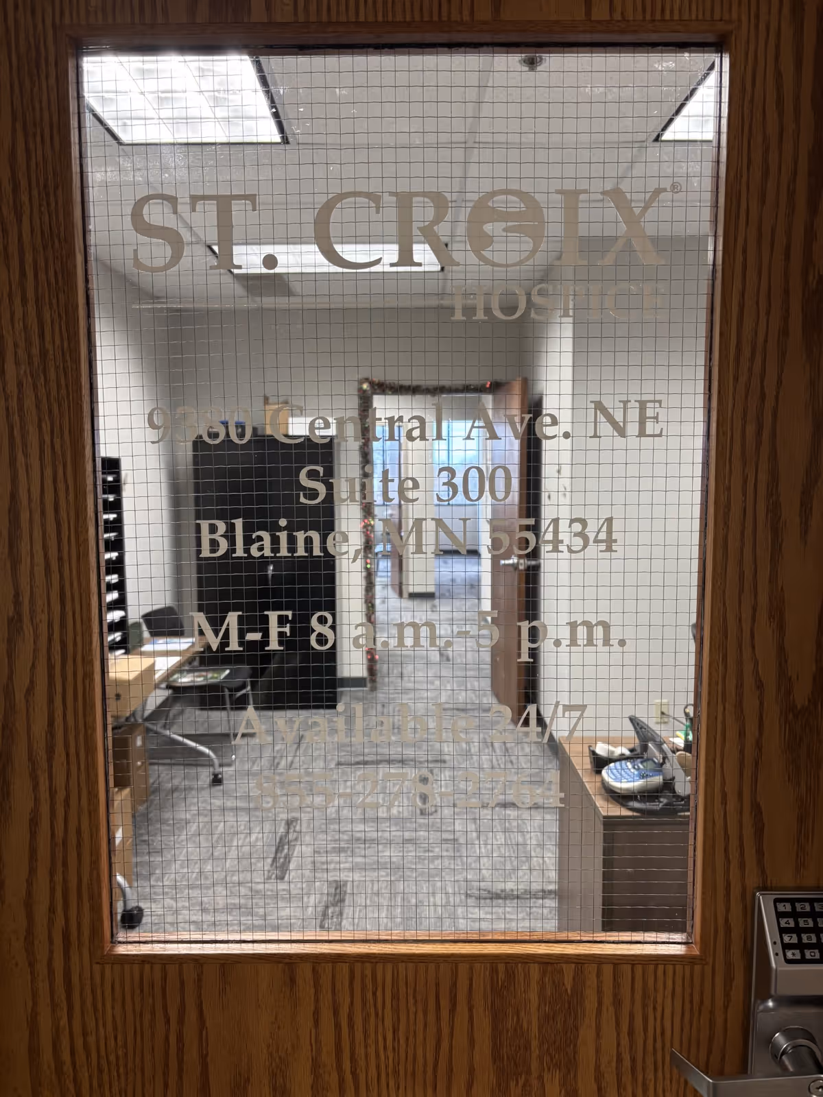 Interior office area viewed through frosted glass door labeled St. Croix Hospice.