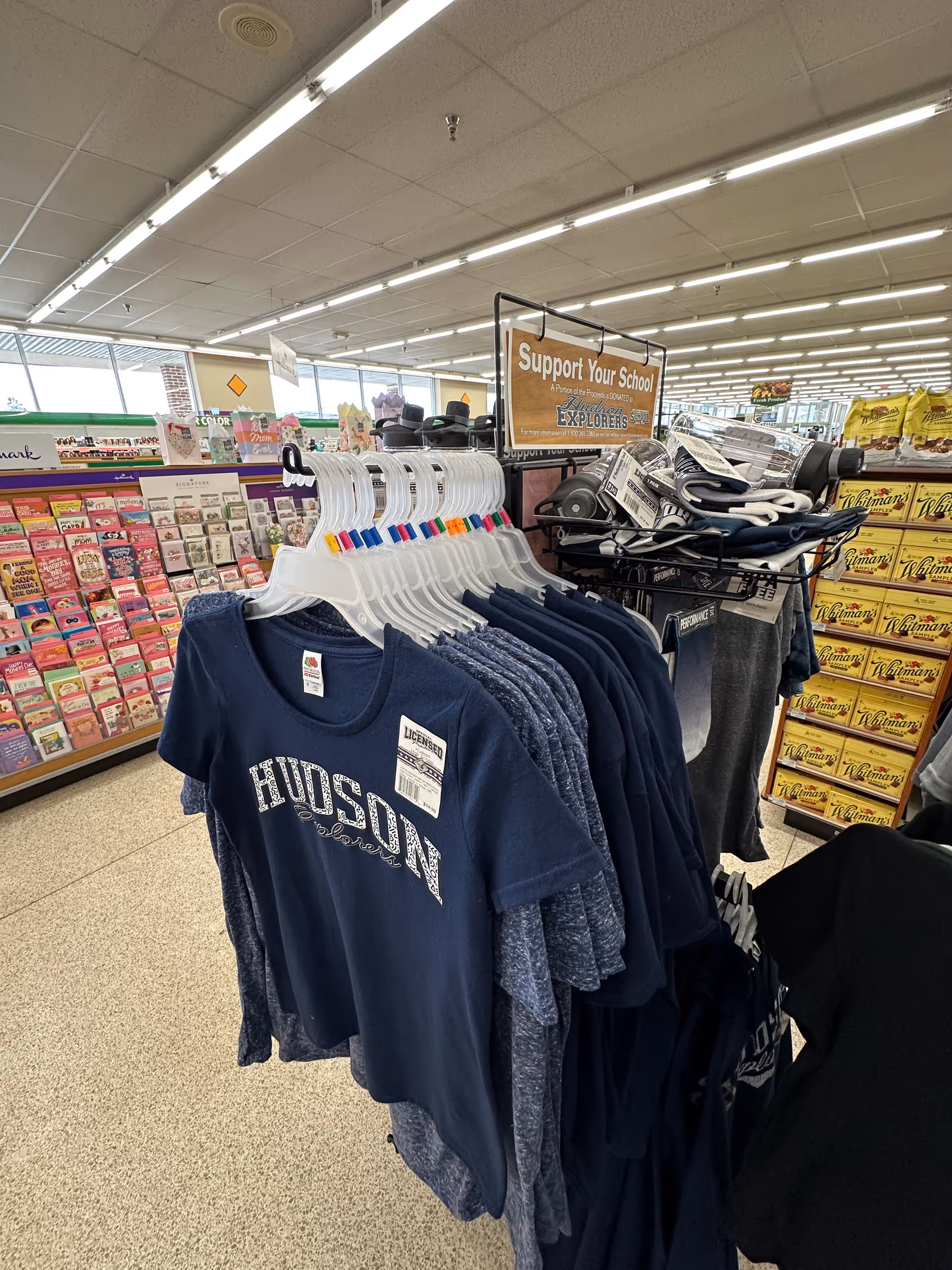 Inside Discount Drug Mart, clothing on racks and greeting cards on shelves.
