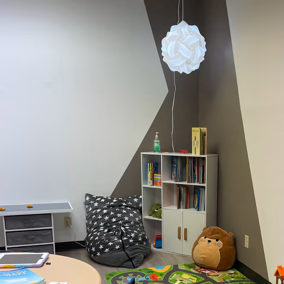 Cozy indoor play nook with star-pattern bean bag, bookshelf, and round pendant lamp.