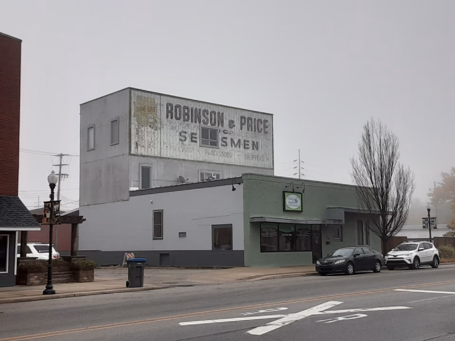 Front view of a two-story building with faded signage and street parking.