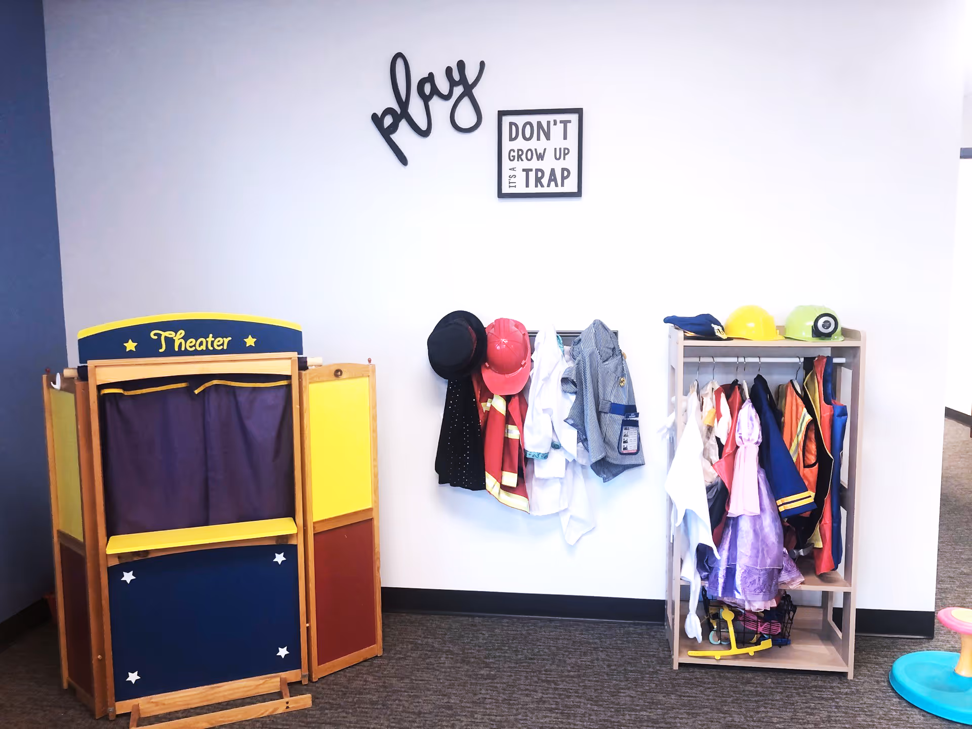 Interior play space featuring a theater booth, costume rack, and hats on display.
