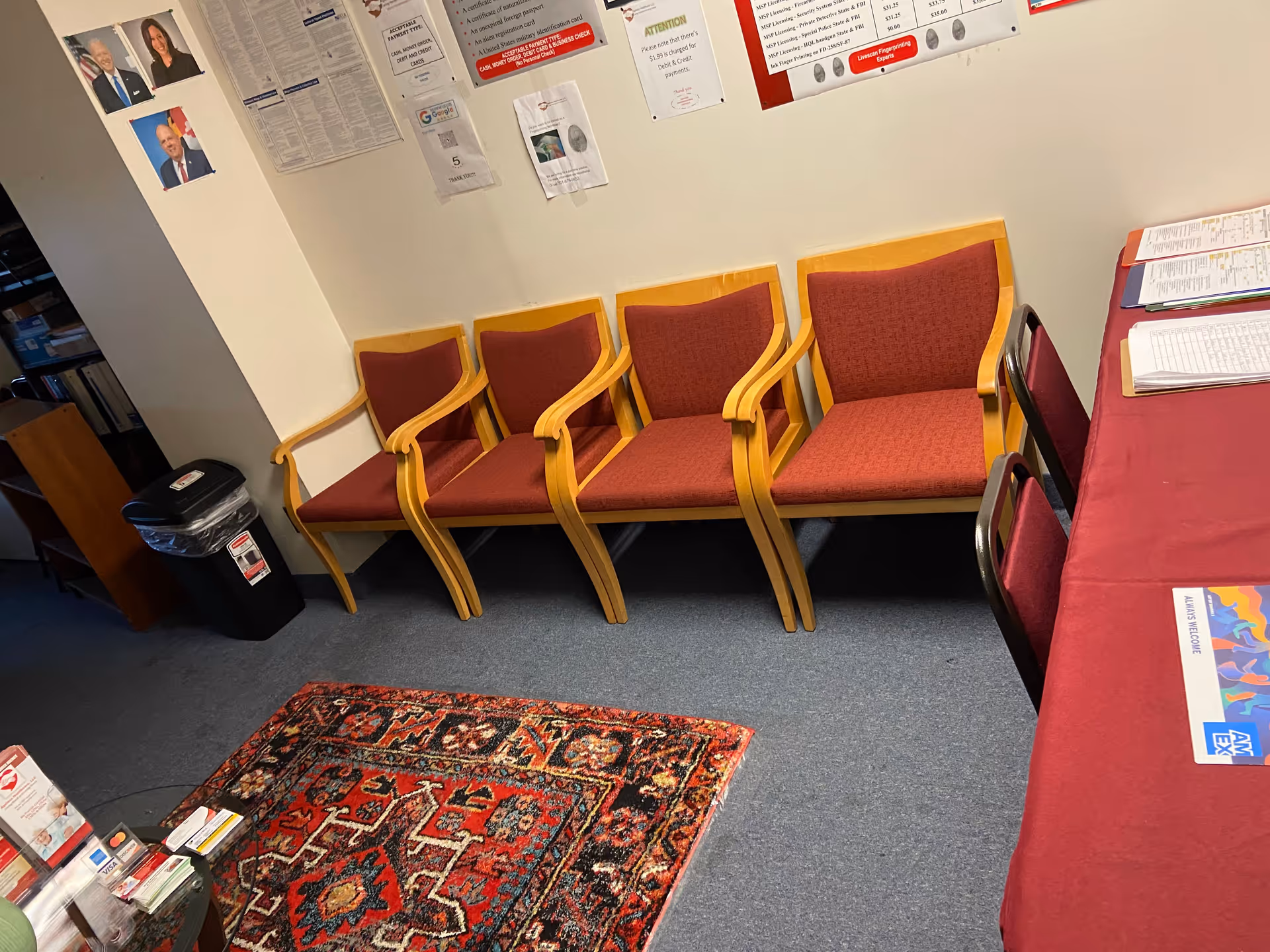 A row of red cushioned chairs along a wall in a waiting area.