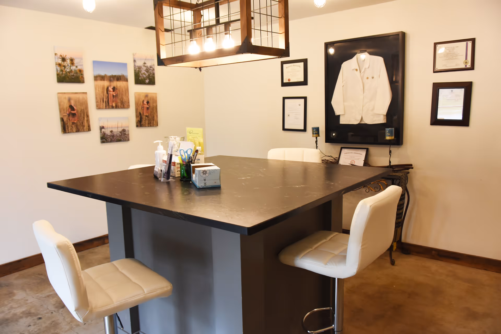 Modern interior with a high black table, white chairs, wall decor, and a displayed white coat.