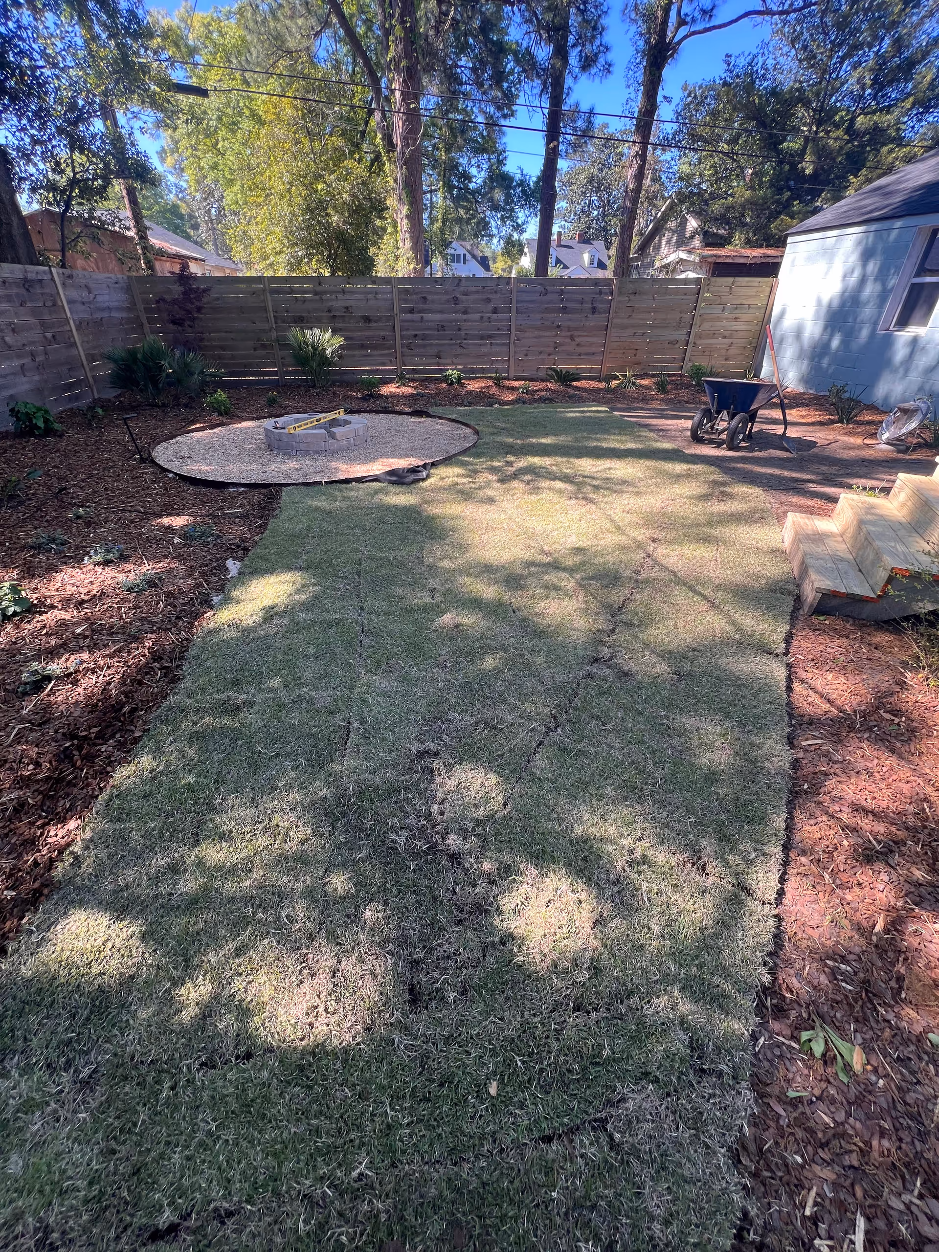 Backyard of a senior care facility with a circular stone fire pit and wheelbarrow