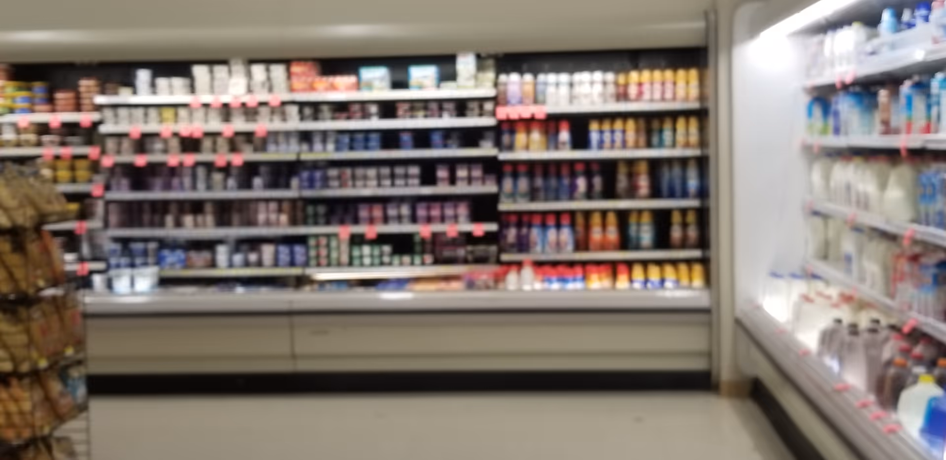 Blurred interior of a Discount Drug Mart with refrigerated displays and product shelves.