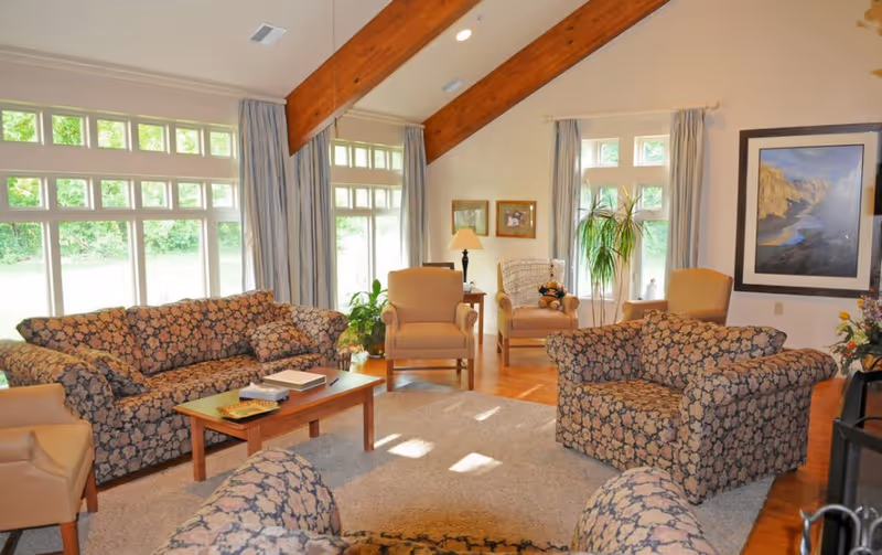 Bright lounge area with patterned sofas, armchairs, and large windows.