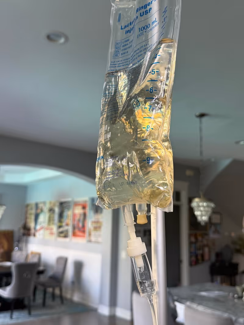 IV bag with tubing hanging from an IV pole in a bright senior living lobby.