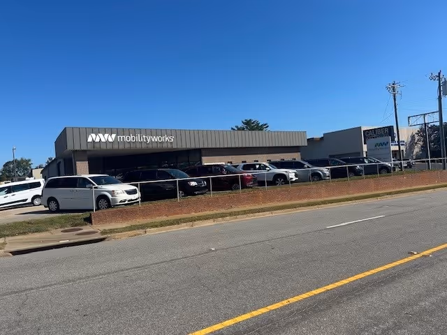 Exterior view of MobilityWorks facility with a row of parked cars along the front entrance.