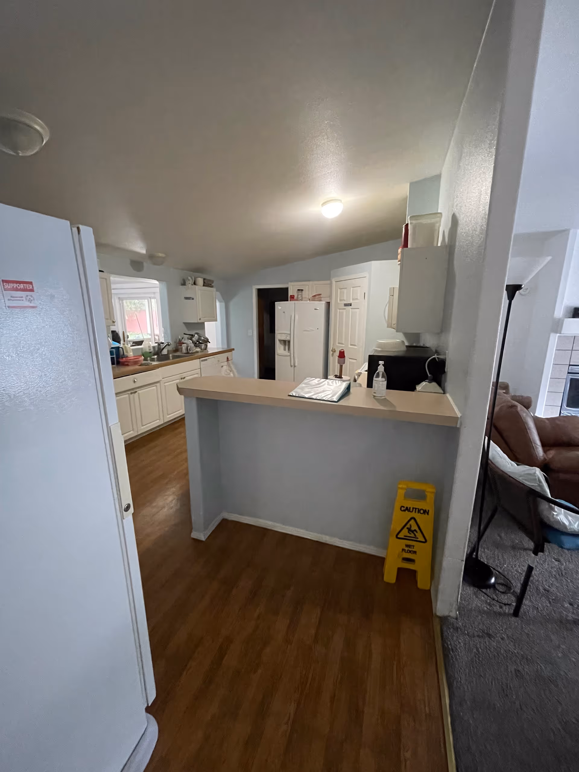 Bright kitchen in a senior living home with white cabinets and a caution sign.