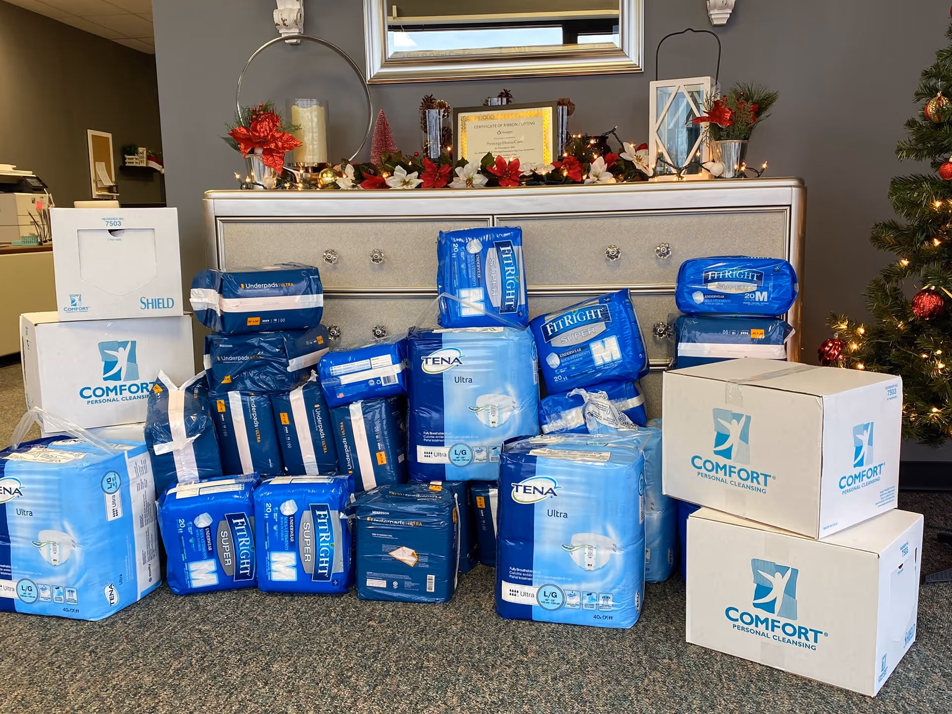 Decorated lobby area with stacked adult care product boxes beside a dresser.