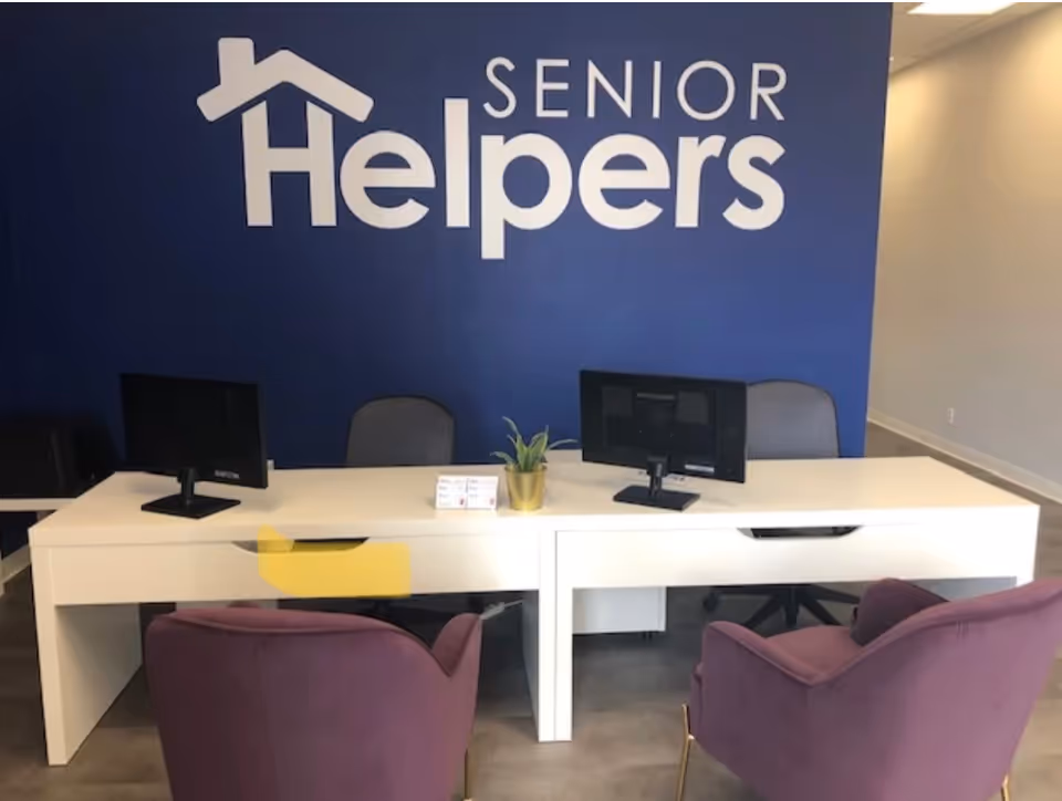 reception desk with computers in a Senior Helpers lobby featuring purple chairs and a blue wall