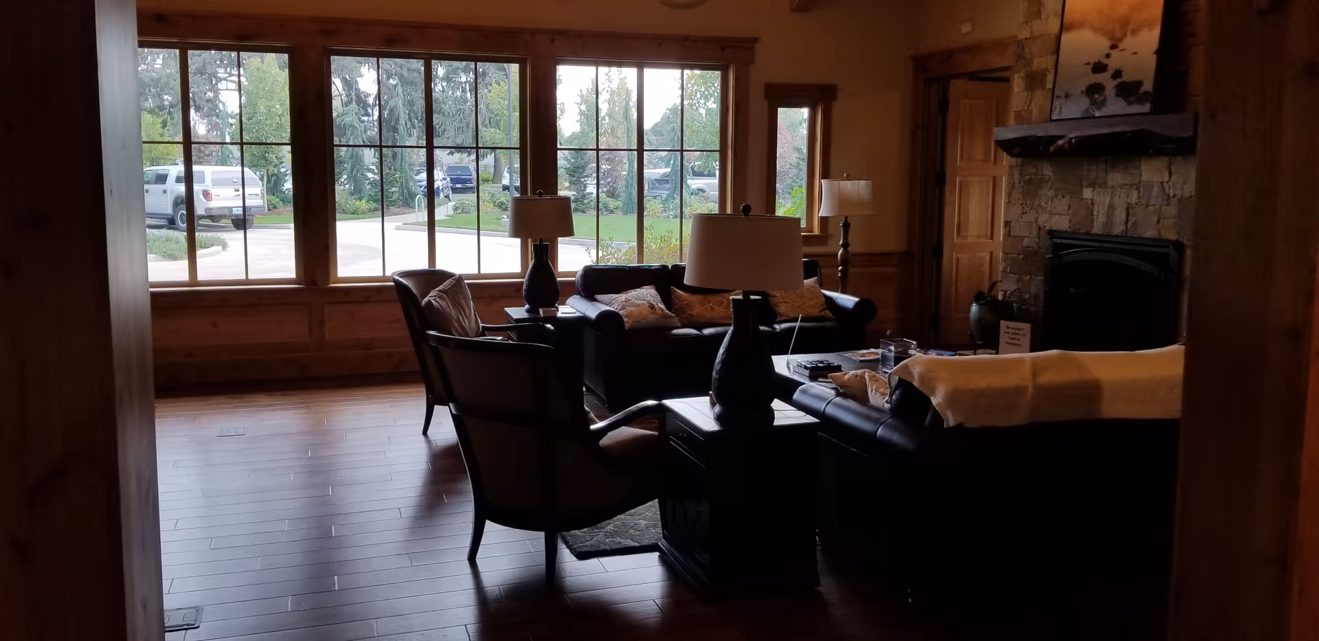 Cozy living room with leather seating, lamps, a fireplace, and large windows.