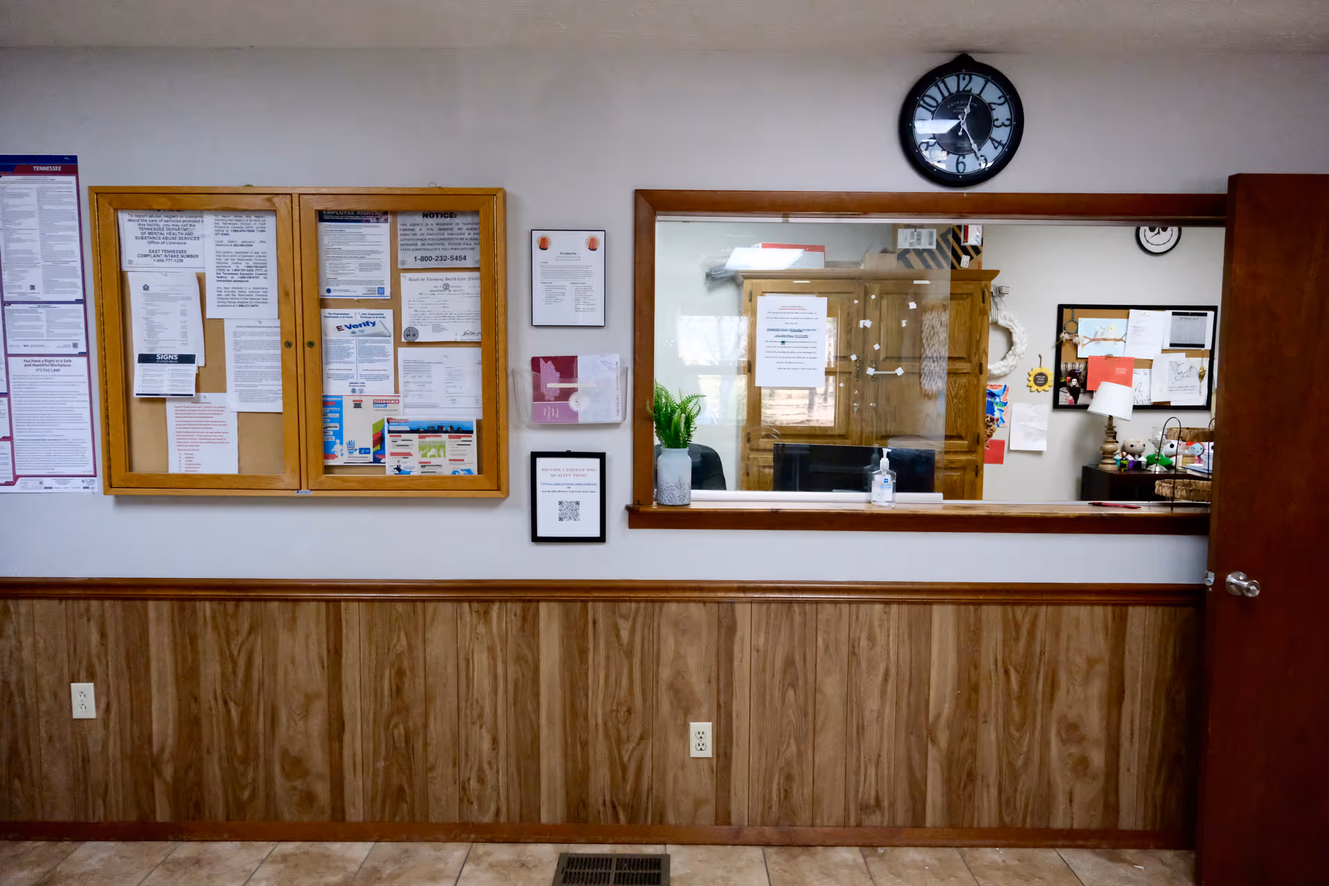 Interior hallway with bulletin boards, a reception window, and wood-paneled walls.