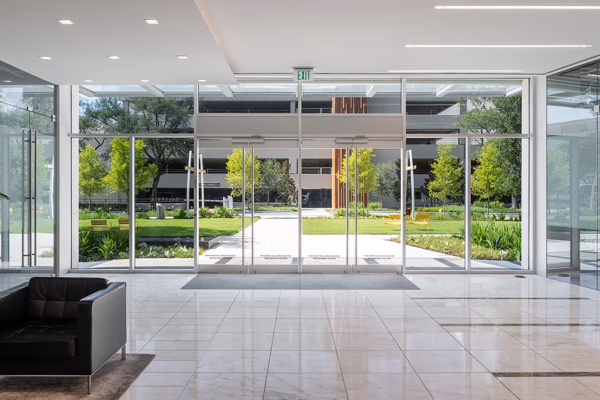 Bright lobby with expansive glass doors revealing a green outdoor courtyard.