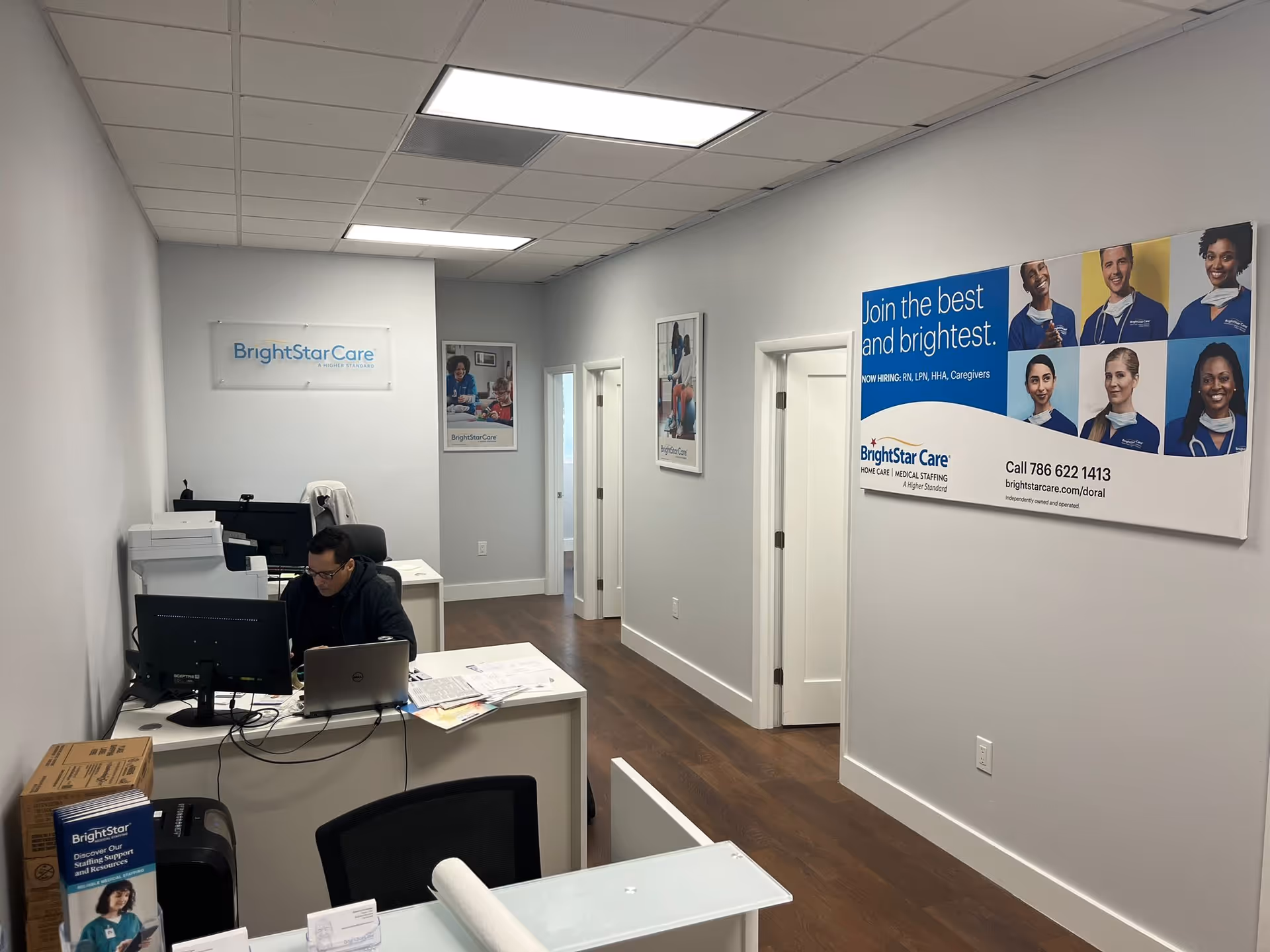 Reception area of BrightStar Care with desk, computer, and hallway posters.