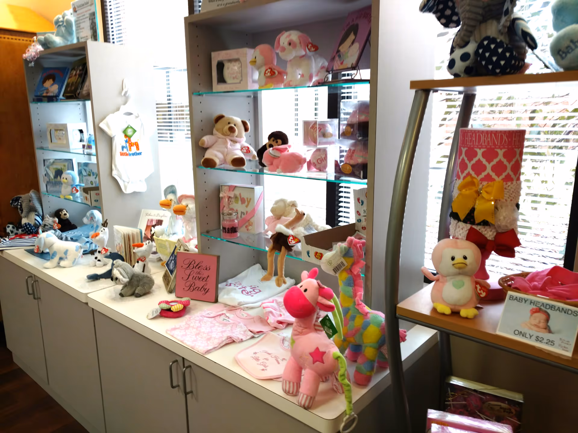 Shelves filled with stuffed animals, toys, and pink baby items inside a bright interior.
