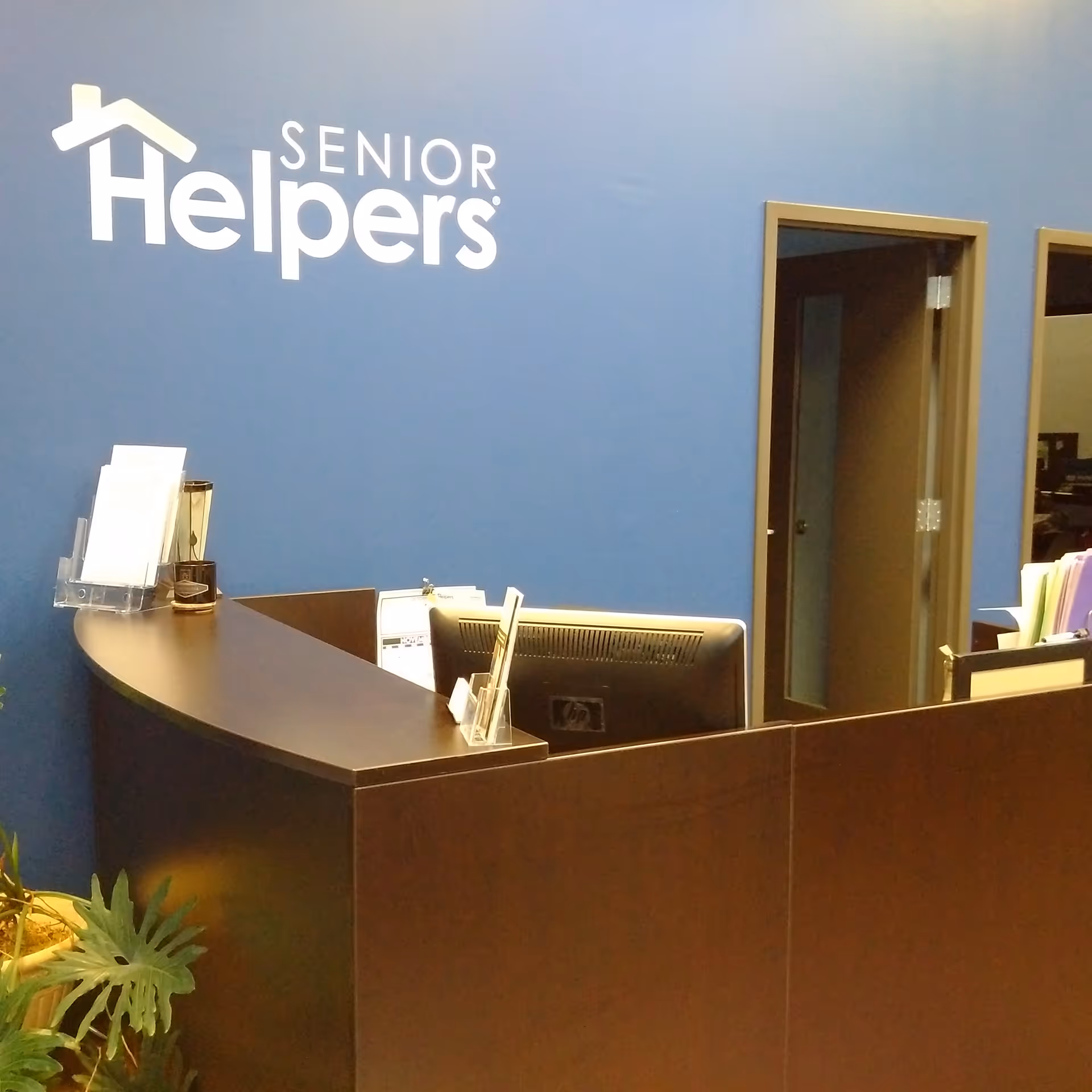 Reception desk in Senior Helpers lobby featuring blue wall and logo.