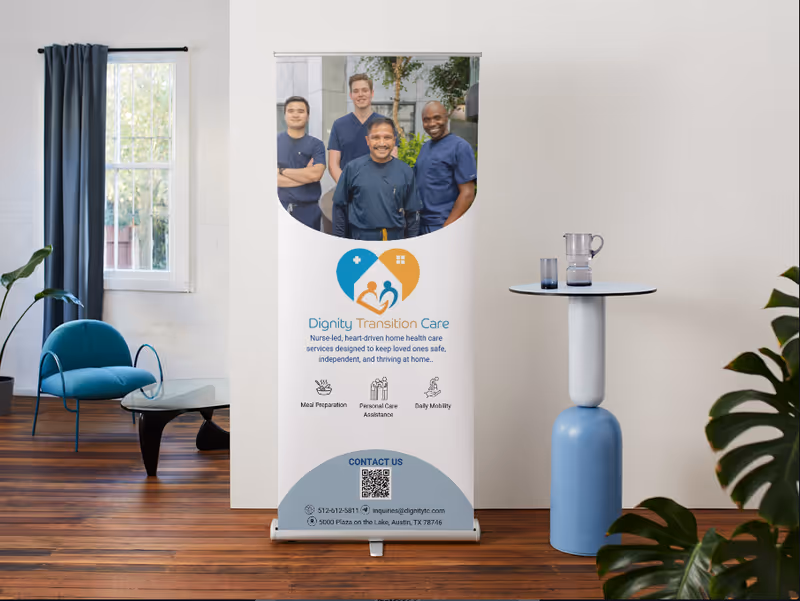 Indoor lobby with Dignity Transition Care banner, blue seating, and a round-topped table.