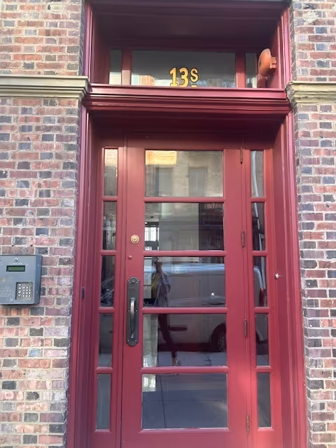 Red-framed glass door at brick building entrance with 13S above.