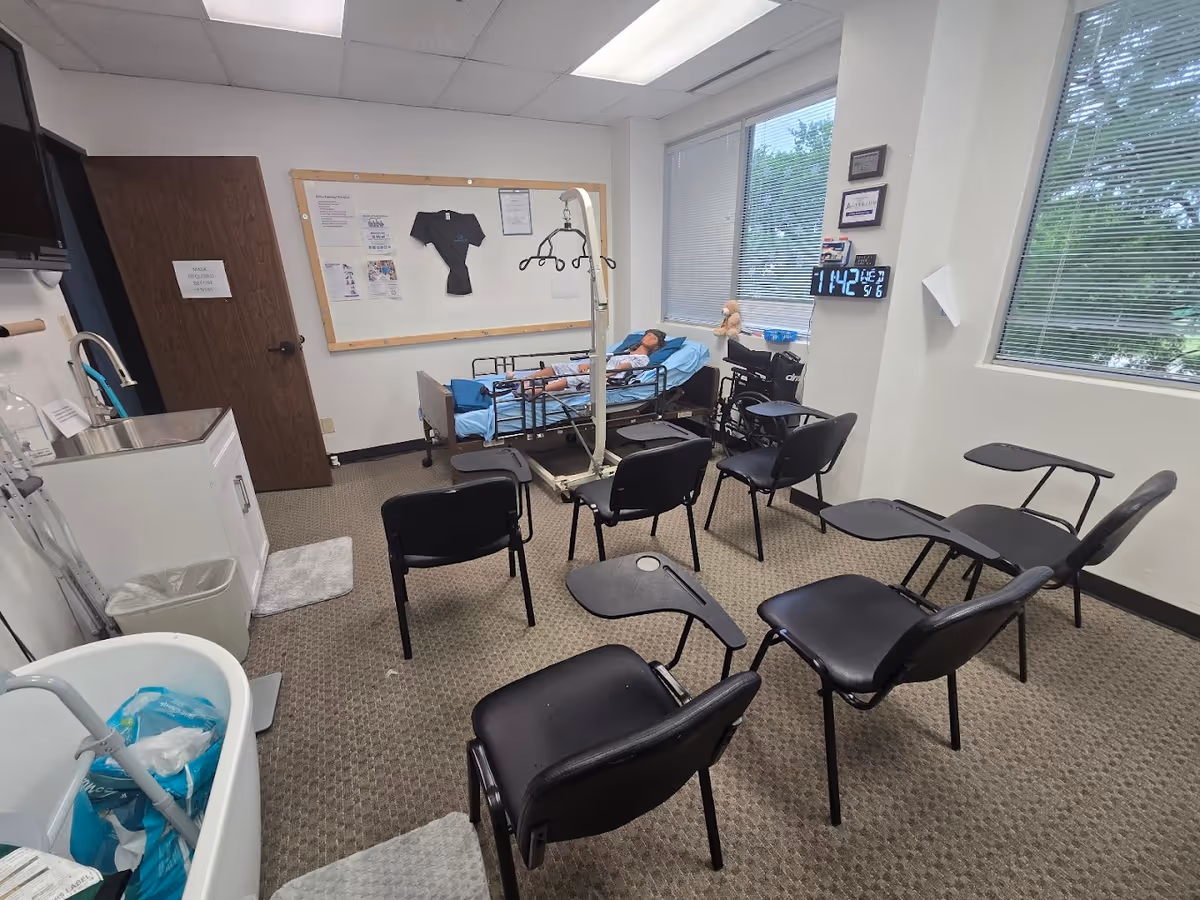 A medical care room with a patient in bed, an IV pole, and row of chairs.