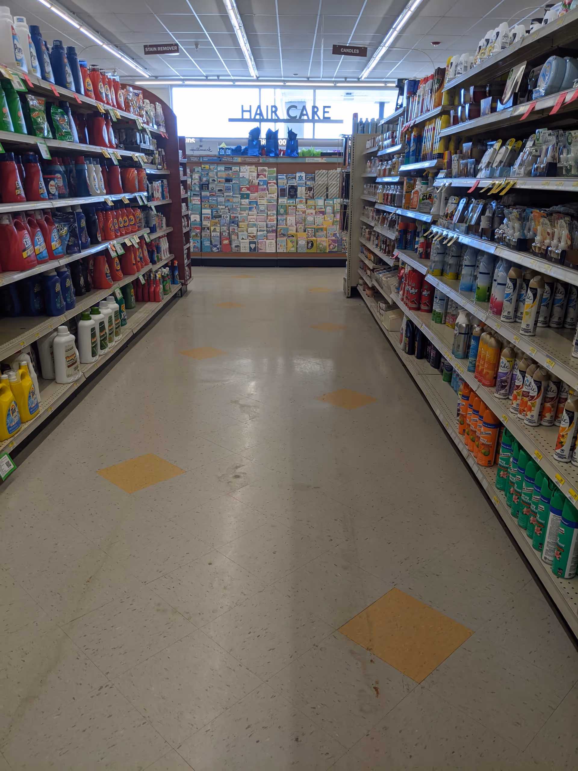 Interior of Discount Drug Mart; long aisle with cleaning products and hair care at the end.