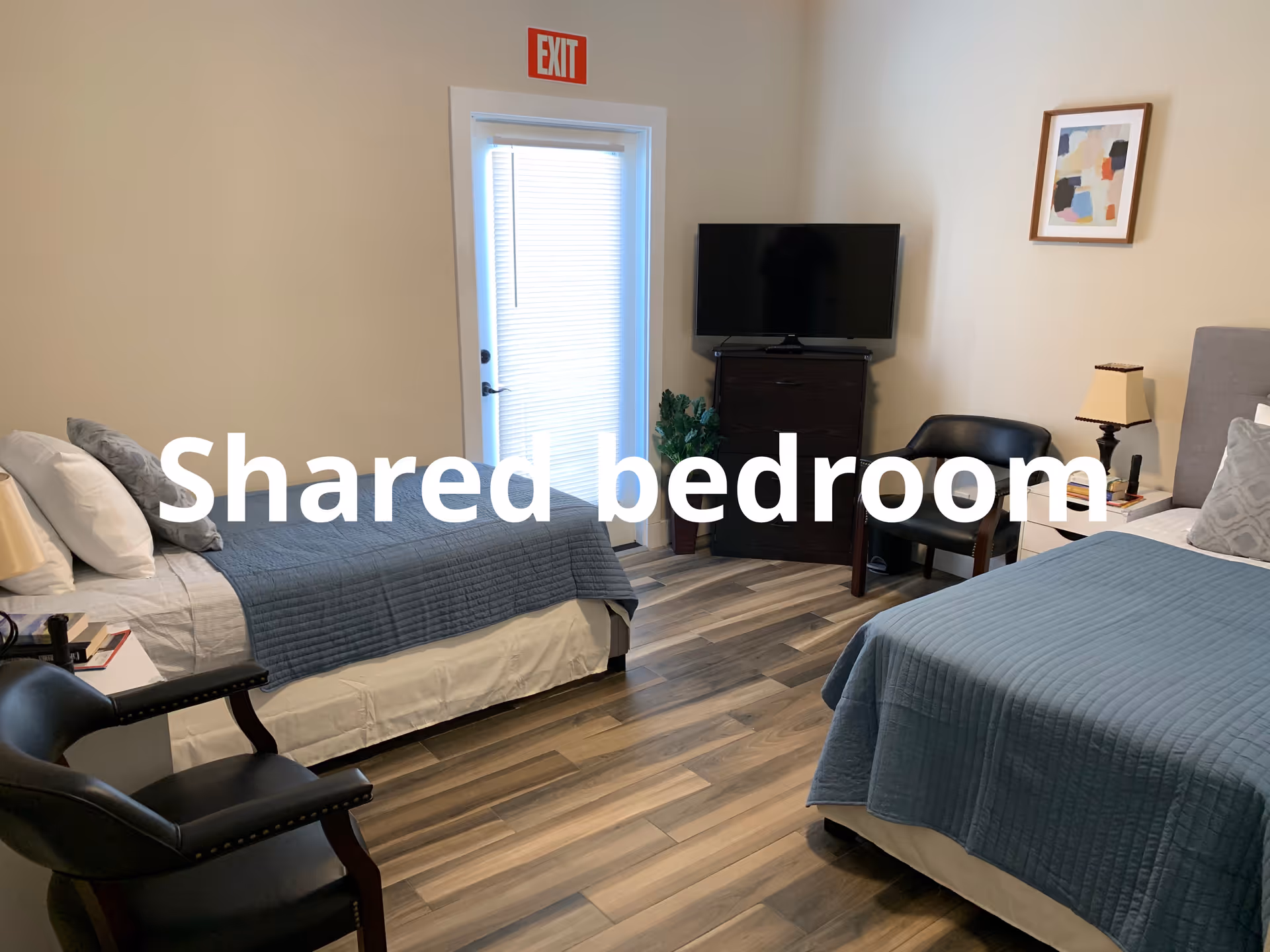 Two beds in a shared bedroom with TV and seating area.