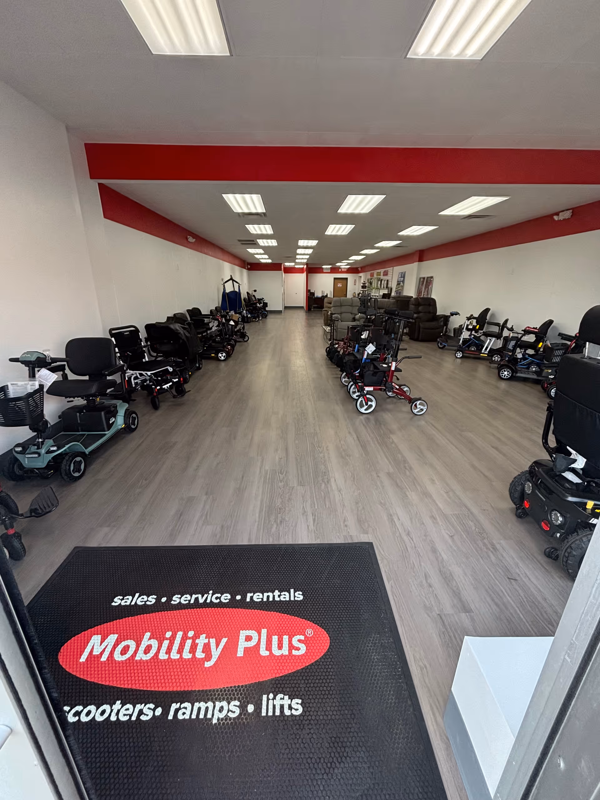 Mobility Plus showroom interior with scooters, ramps, and chairs arranged along walls.