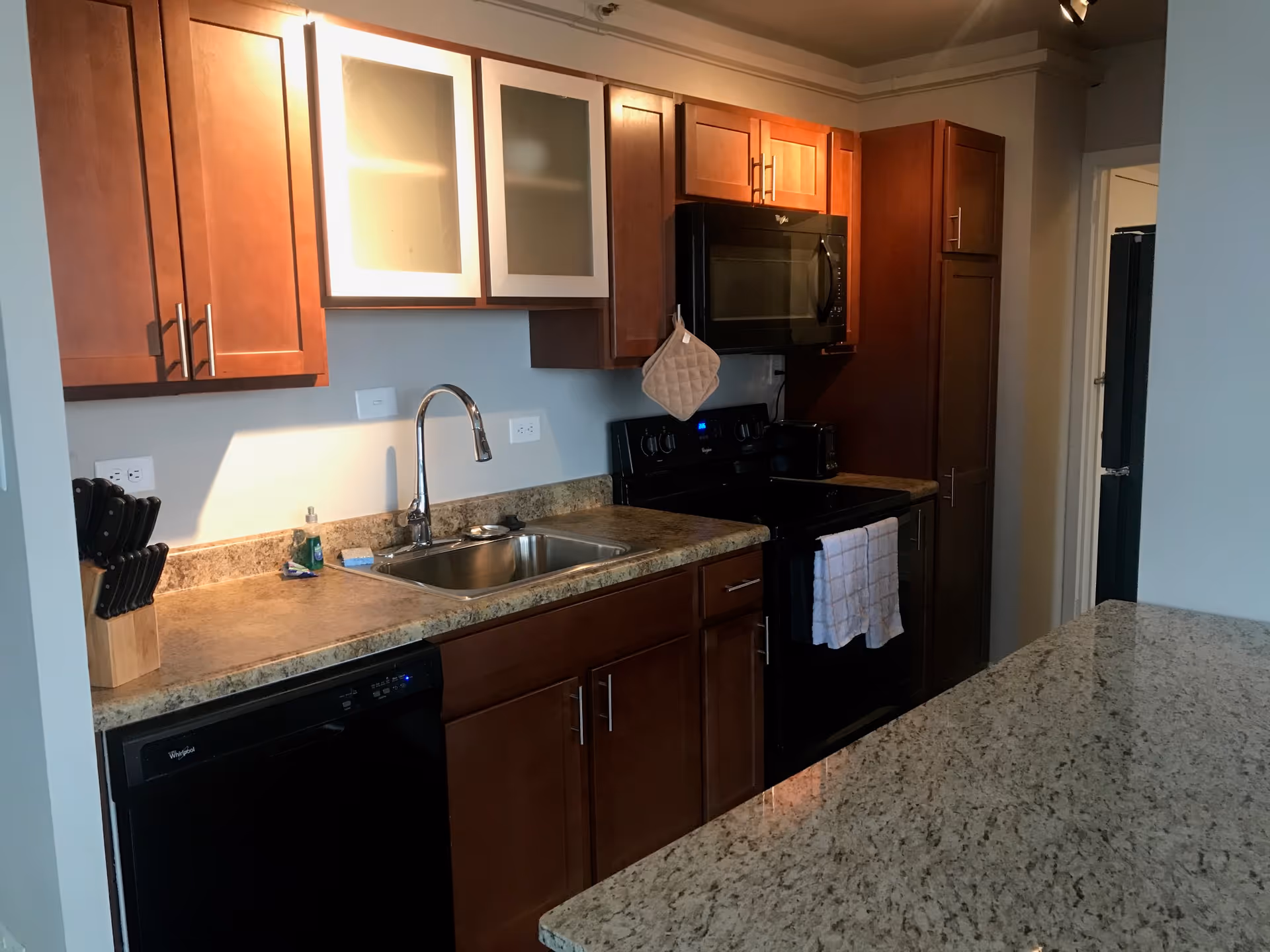 Modern kitchen with wood cabinets, granite countertops, sink, and stainless appliances.