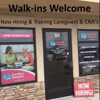 Storefront of Comfort Keepers In Home Care with Walk-ins Welcome and Now Hiring signs.