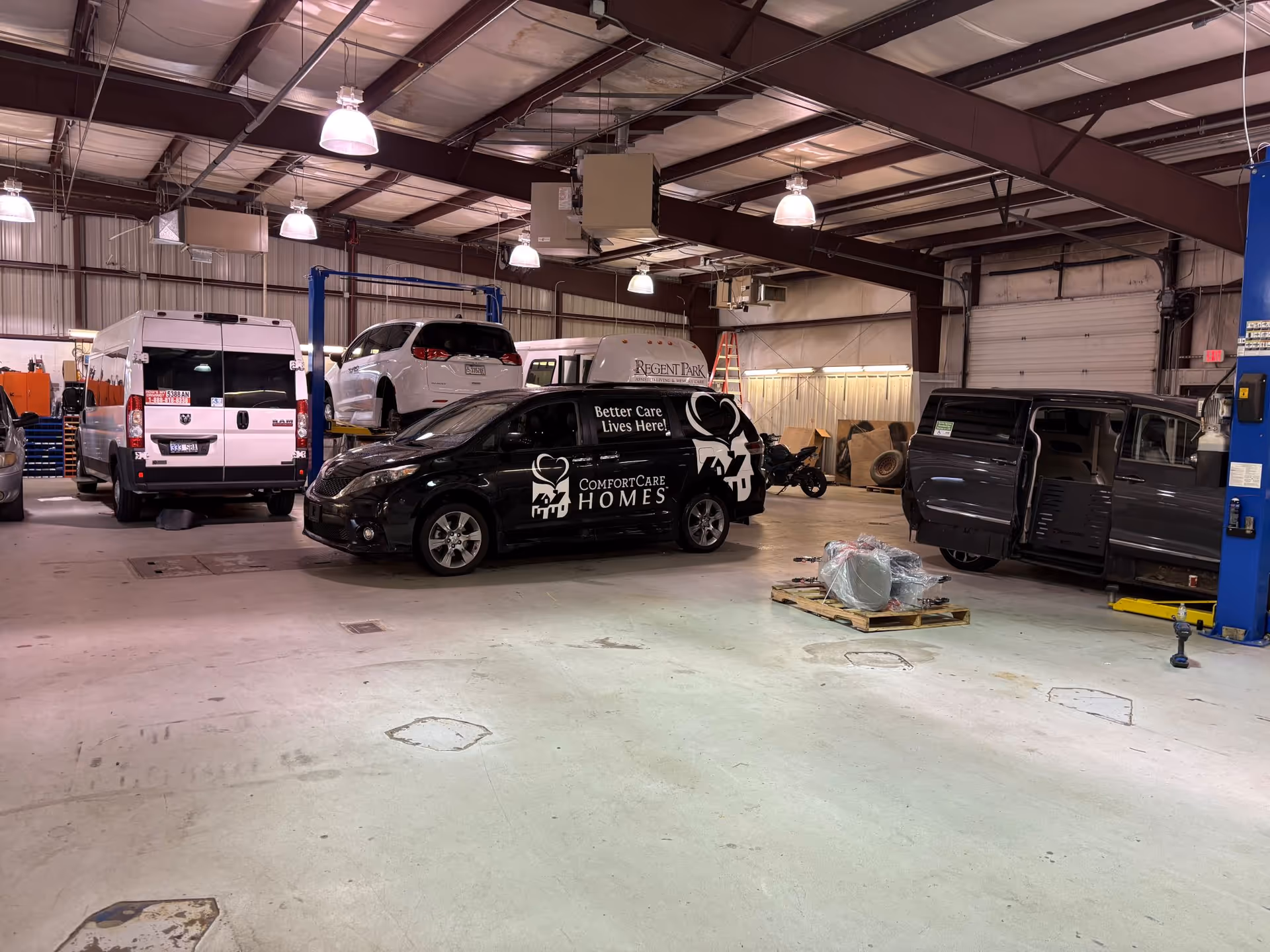 Industrial indoor workshop with mobility vans on lifts and assorted equipment