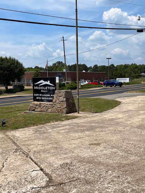 Exterior view of a building front with a stone sign along a road.