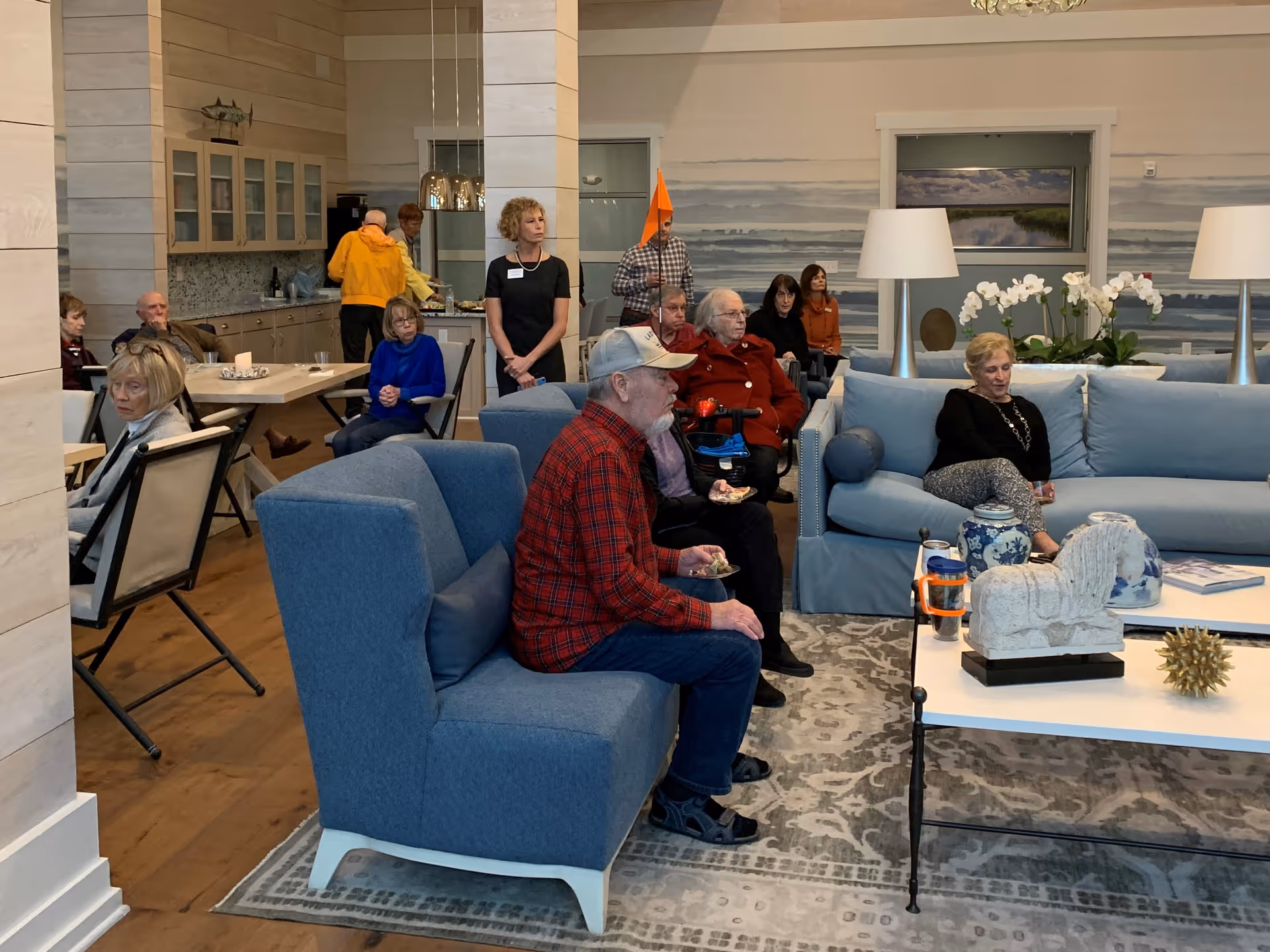 Group of seniors seated on blue sofas in a cozy communal living room.