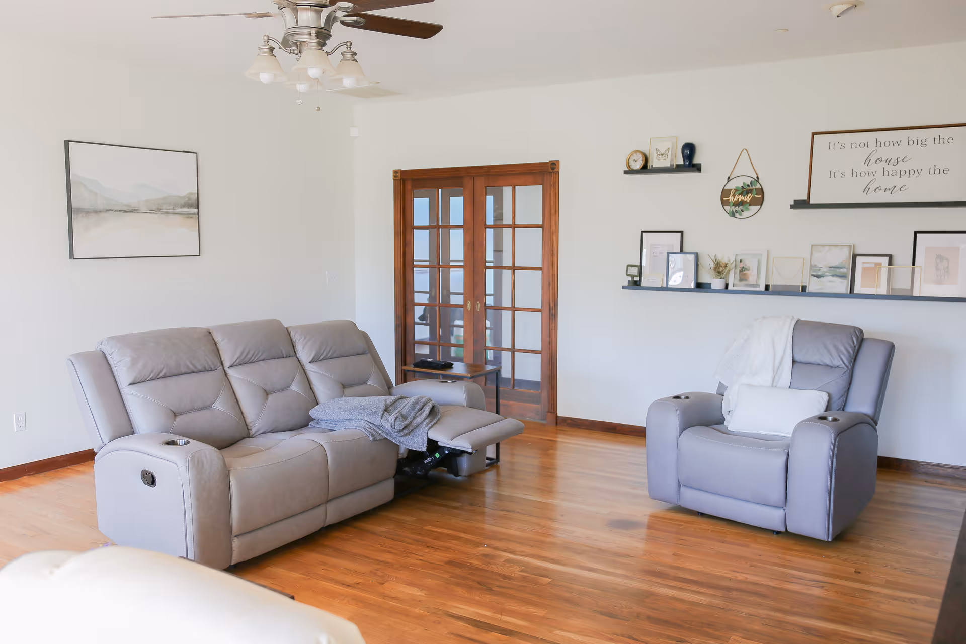 Cozy living room with reclining sofa and matching armchair, wooden floor, decor.